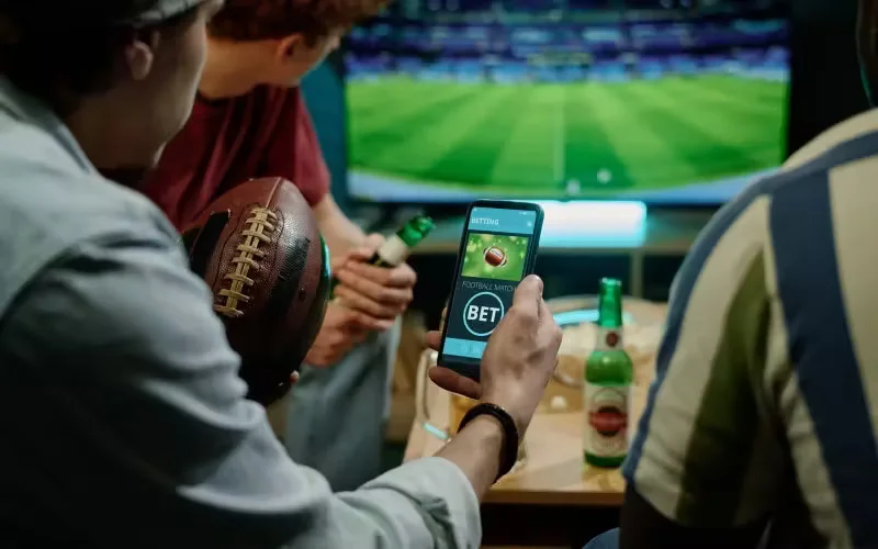 Dedicated Bangladeshi fan placing quick bets on phone and laptop during a tense live cricket match